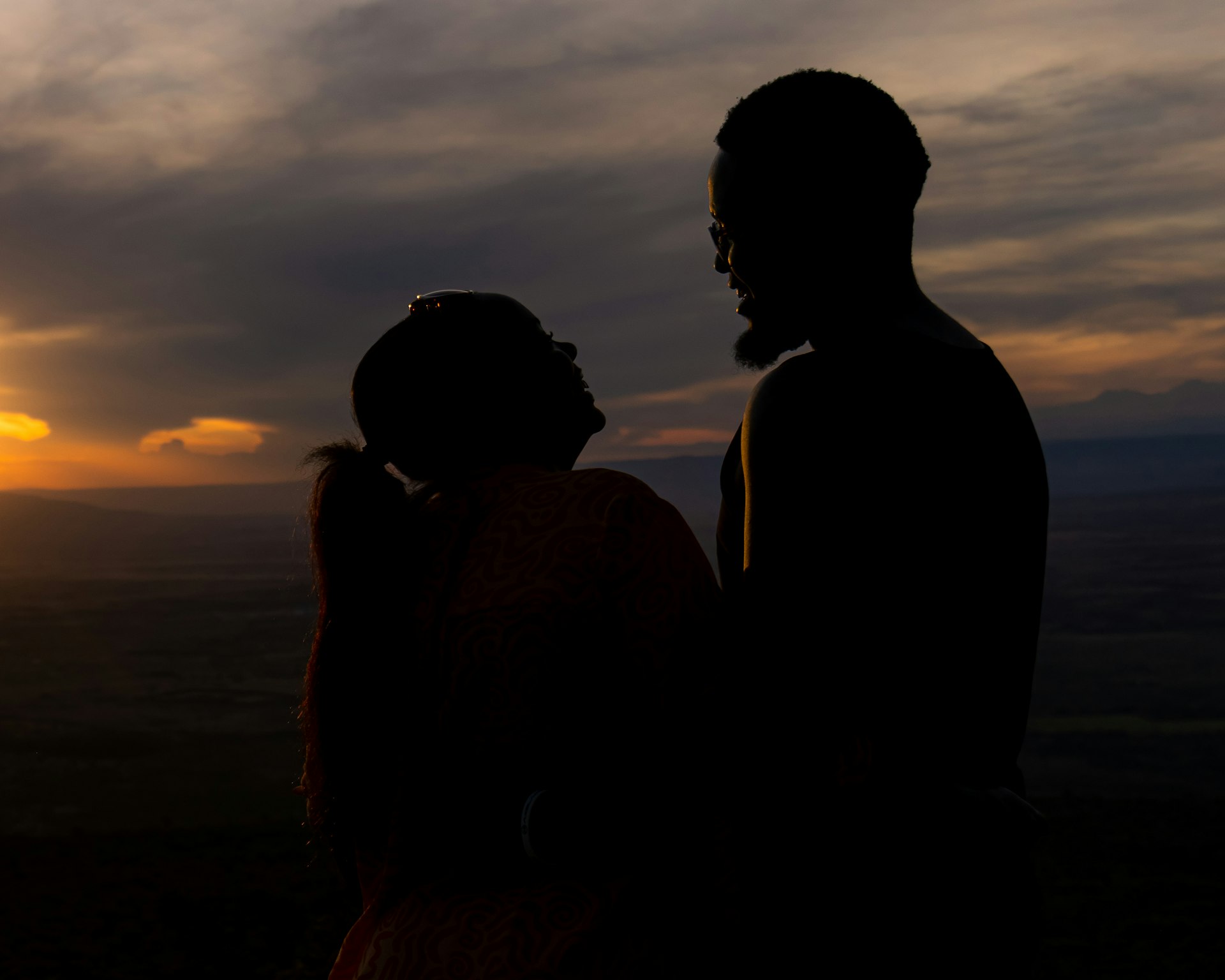A man and a woman standing in front of a sunset